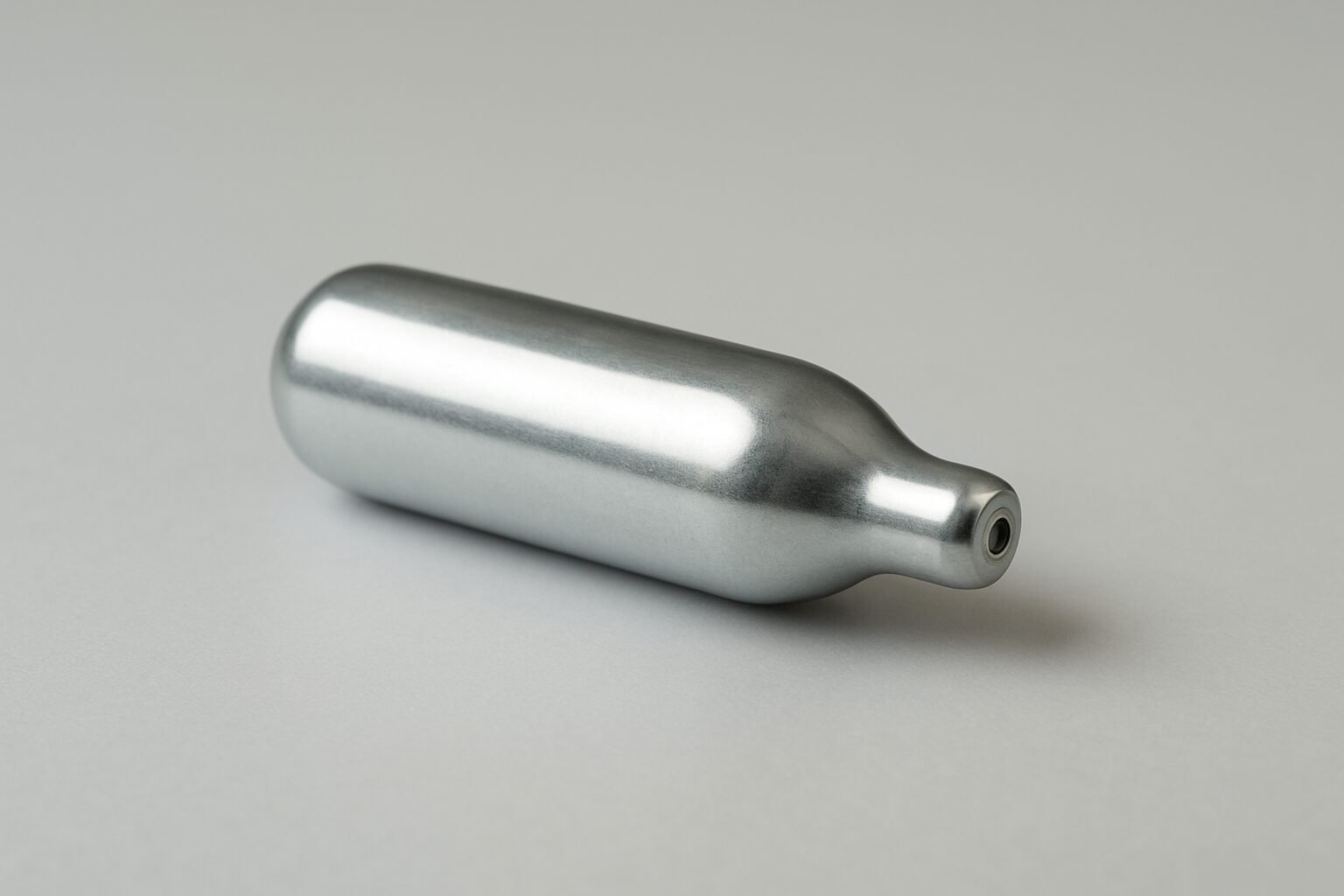 A metallic nang canister on a plain surface